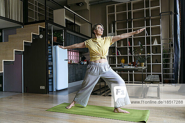 Woman practicing yoga at home doing warrior pose