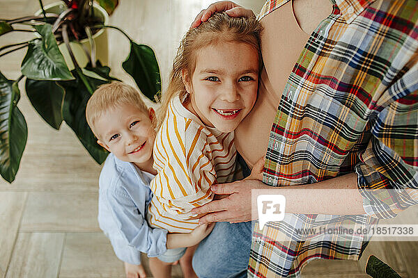 Happy children embracing mother at home