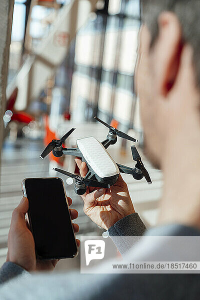 Businessman holding drone and smart phone in office