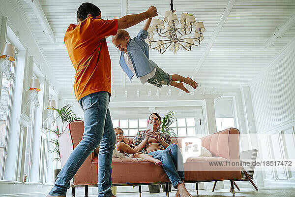 Playful father spinning son in living room