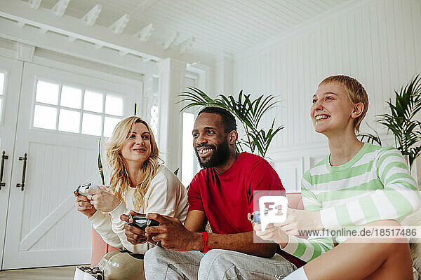 Happy multiracial friends playing video game together at home