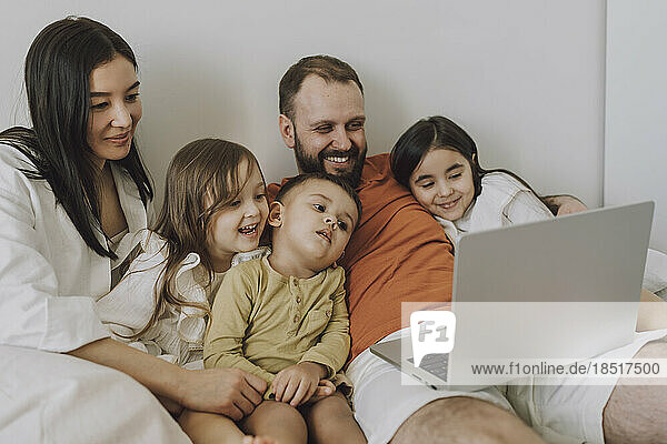 Smiling family using laptop together at home