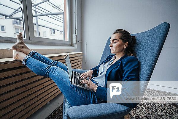 Businesswoman using laptop in armchair at office