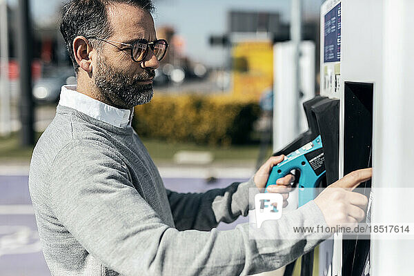 Man operating kiosk at electric car charging station