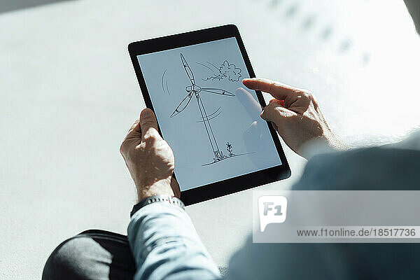 Businessman with wind turbine drawing on tablet PC in office