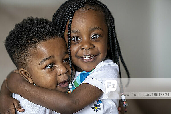 Cute girl embracing brother at home
