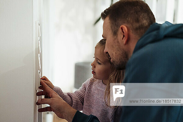Mädchen und Vater regeln zu Hause die Temperatur am Thermostat