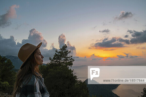 Frau mit Hut genießt den Sonnenuntergang im Urlaub