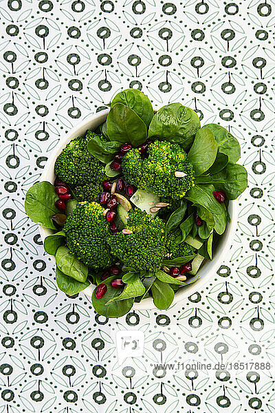 Bowl of green salad with broccoli  corn salad  cashews  cucumber and various seeds