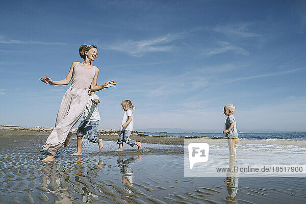 Fröhliche Mutter spielt mit Kindern am Strand