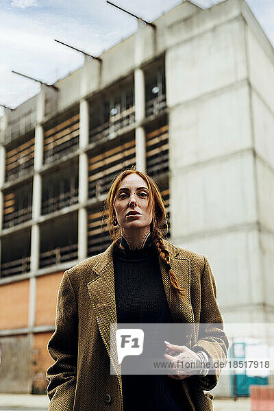 Redhead woman wearing coat standing in front of building