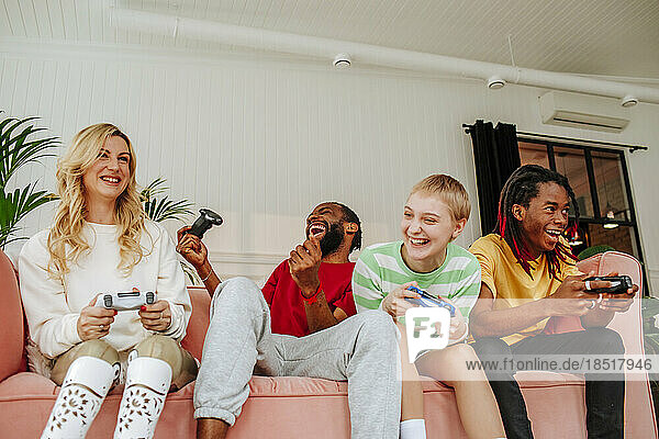 Excited young man playing video game with friends on sofa