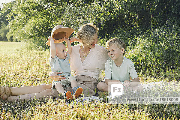 Happy mother sitting with sons in nature