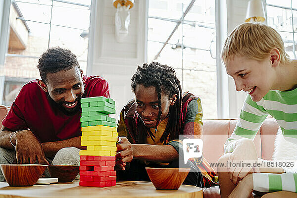 Happy young man playing block removal game with friends