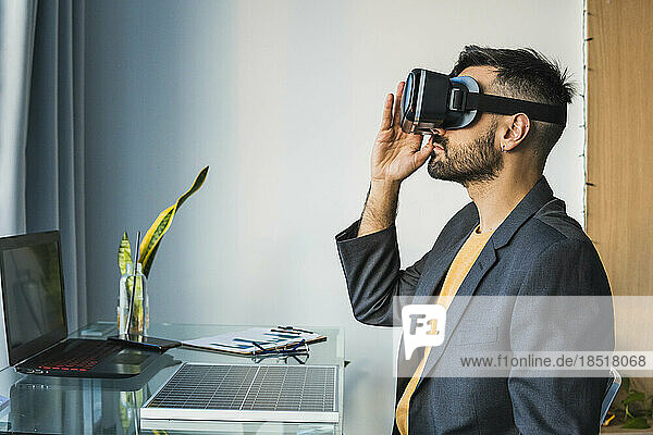Businessman adjusting virtual reality headset sitting at home office