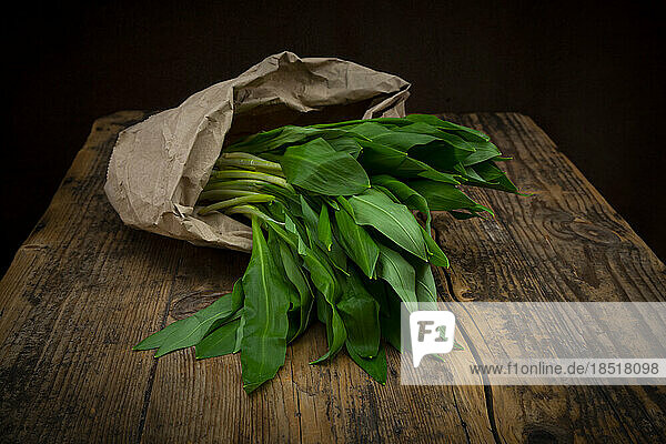 Fresh ramson in paper bag lying on wooden table