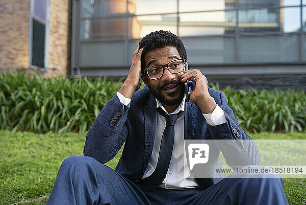 Shocked businessman talking on smart phone outside office building