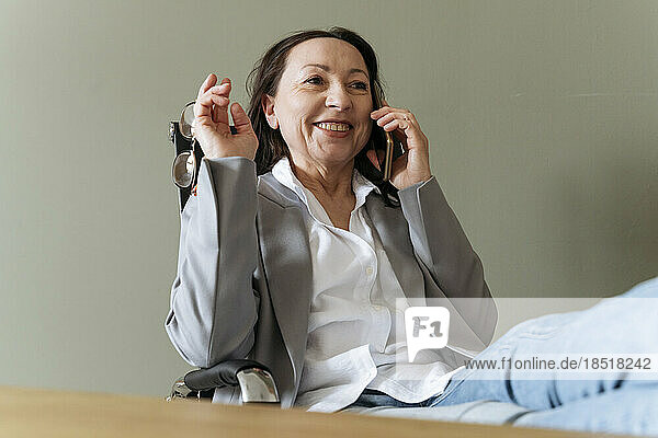Happy businesswoman talking on mobile phone sitting at office