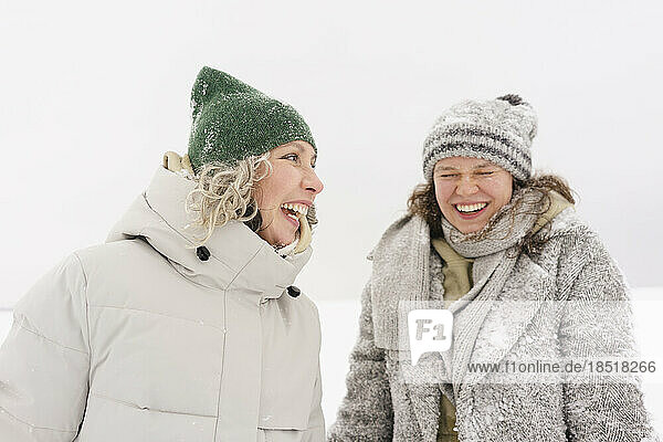 Cheerful woman enjoying with friend in snow