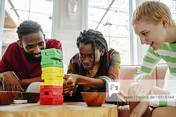 Lächelnder junger Mann  der mit Freunden ein Blockentfernungsspiel spielt
