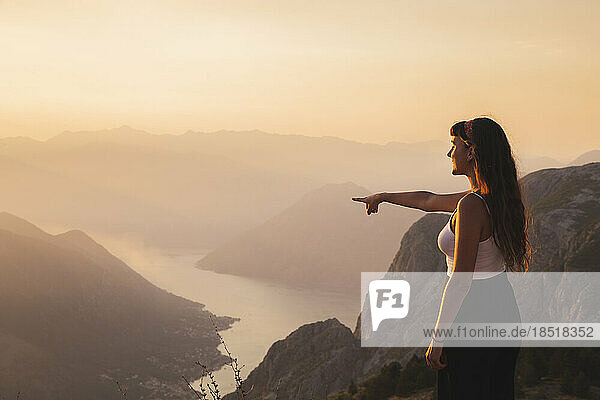 Young woman gesturing towards mountains
