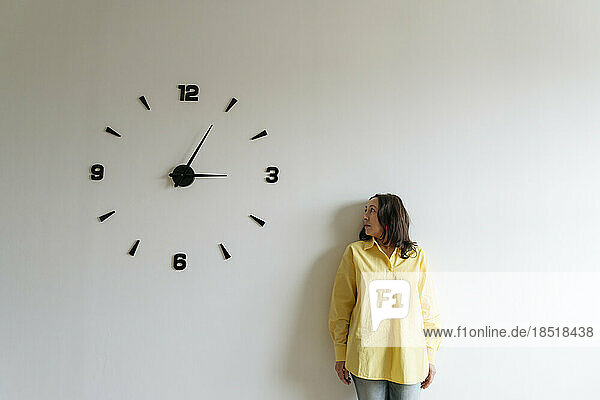 Woman looking at large clock on white wall