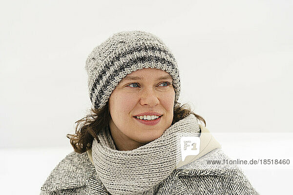 Thoughtful smiling woman wearing knit hat in winter