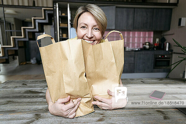 Happy woman with paper bags on table at home