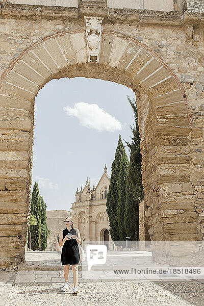 Woman standing in front of arch on sunny day