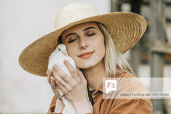 Farmer wearing straw hat holding dove