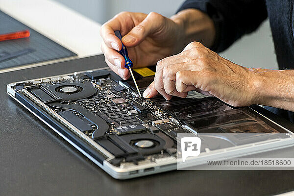 Man repairing laptop with screwdriver