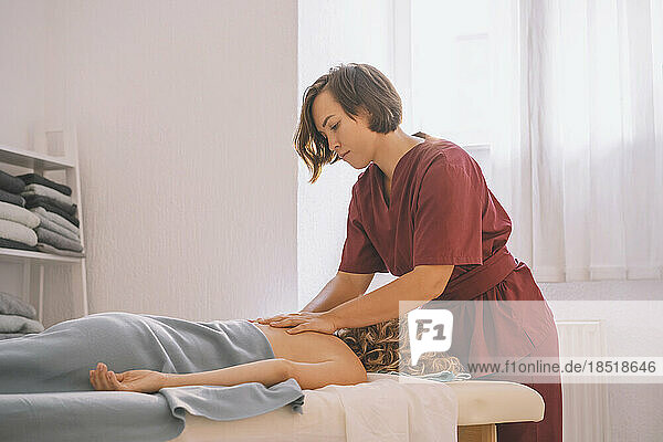 Therapist giving back massage to customer in spa