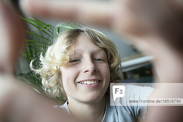 Happy blond boy looking through finger frame