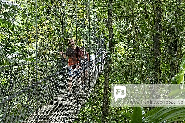 La Fortuna  Costa Rica  Tourists cross a suspension bridge in the rain in Mistico Hanging Bridges Park. The park allows tourists to hike through the rain forest  including at treetop canopy levels on several long suspension bridges  Central America