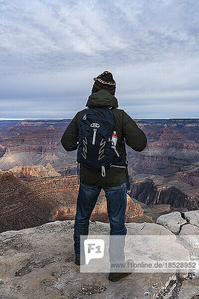 United States  Arizona  Grand Canyon National Park  South Rim  Senior male hiker standing at edge of Grand Canyon at sunrise 