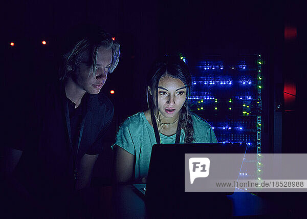 Technicians using laptop in server room