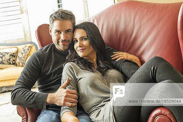 Couple sitting on armchair together in living room 