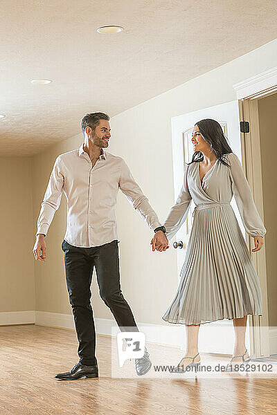 Couple holding hands and walking in to new apartment 