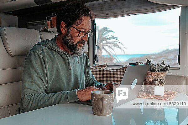 Man sitting in mobile home and working on laptop