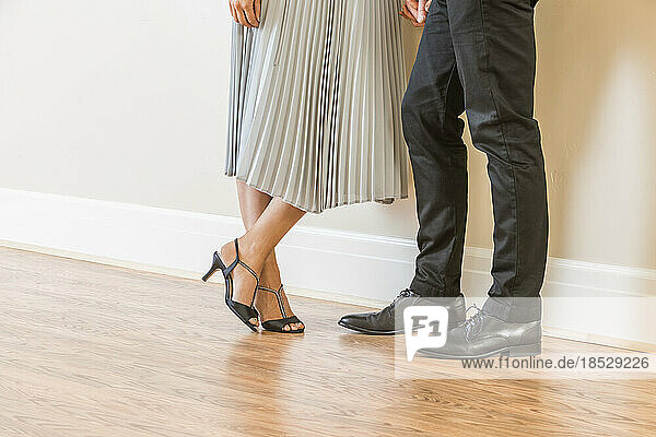 Low section of couple standing on wooden floor in apartment 