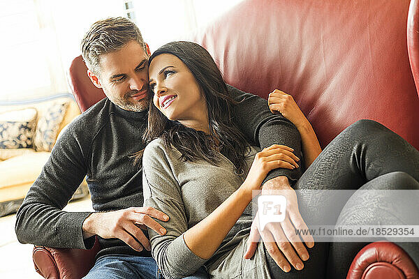 Man embracing woman sitting on armchair