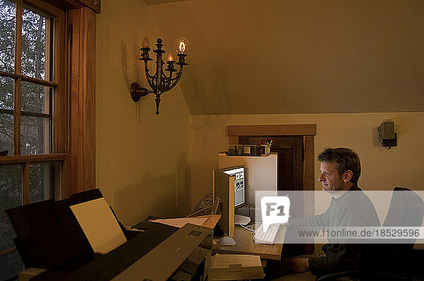 Mann arbeitet an einem Computer in einem Heimbüro; Lincoln  Nebraska  Vereinigte Staaten von Amerika
