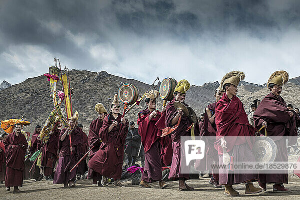 Buddhistische Mönche spielen Musik  während sich Pilger niederwerfen; Langmusi  Amdo  China