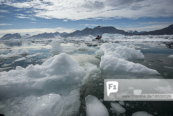 Visitors to Greenland's Nansen Fjord cruise around icebergs in the area where a glacier enters the water; Greenland
