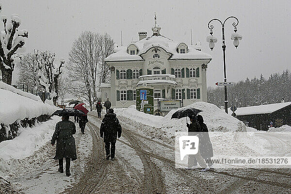Touristen tragen Regenschirme  um während eines Wintersturms in Füssen  Deutschland  die schneebedeckten Straßen hinaufzukommen; Füssen  Deutschland