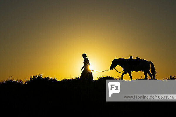Frau führt Pferd  Silhouette bei Sonnenaufgang; Saintes-Maries-de-la-Mer  Frankreich
