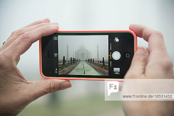 Using a cell phone to take a photo of the Taj Mahal on a foggy day; Agra  India