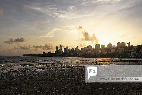 People on Chowpatty Beach at sunset with a view of the skyline in Mumbai; Mumbai  Maharashtra  India