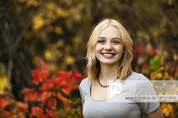 Porträt einer schönen jungen Frau im Teenageralter vor einem Waldhintergrund in einem Stadtpark an einem warmen Herbsttag; St. Albert  Alberta  Kanada
