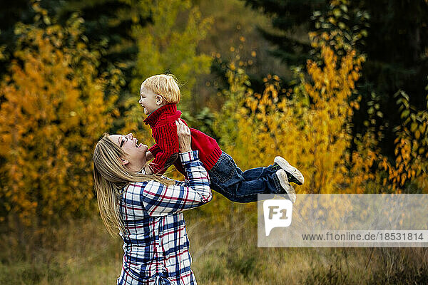 Mother plays outdoors with her young son  lifting him in the air; Edmonton  Alberta  Canada